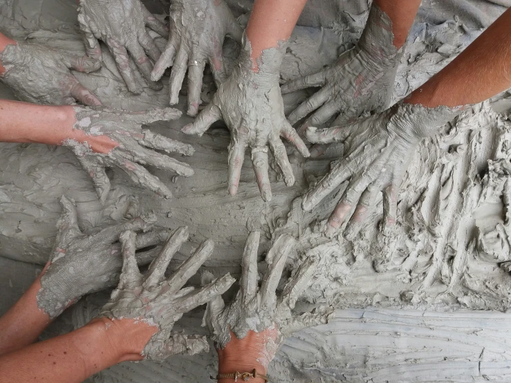 a number of hands on a large pile of mud