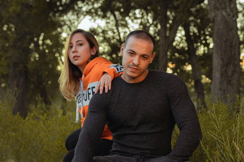 a couple is sitting in the grass posing for a picture