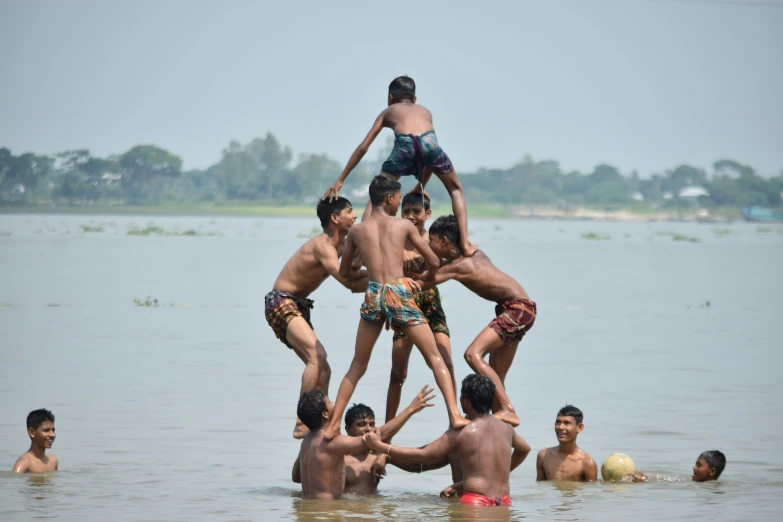 four boys are playing in the water while holding on to their legs