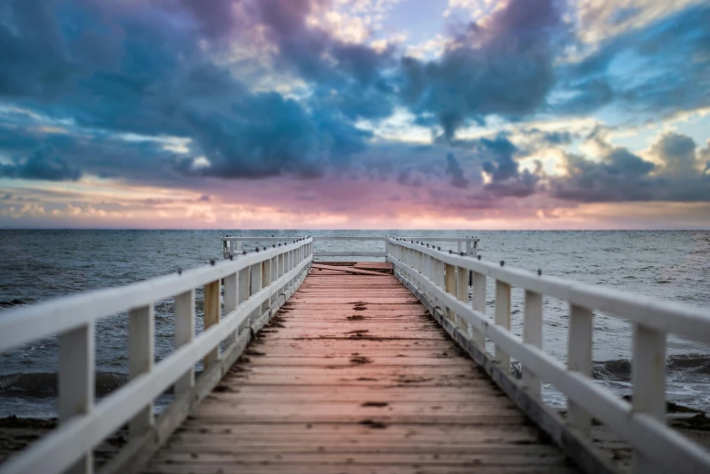 a pier extending into the ocean under a cloudy sky