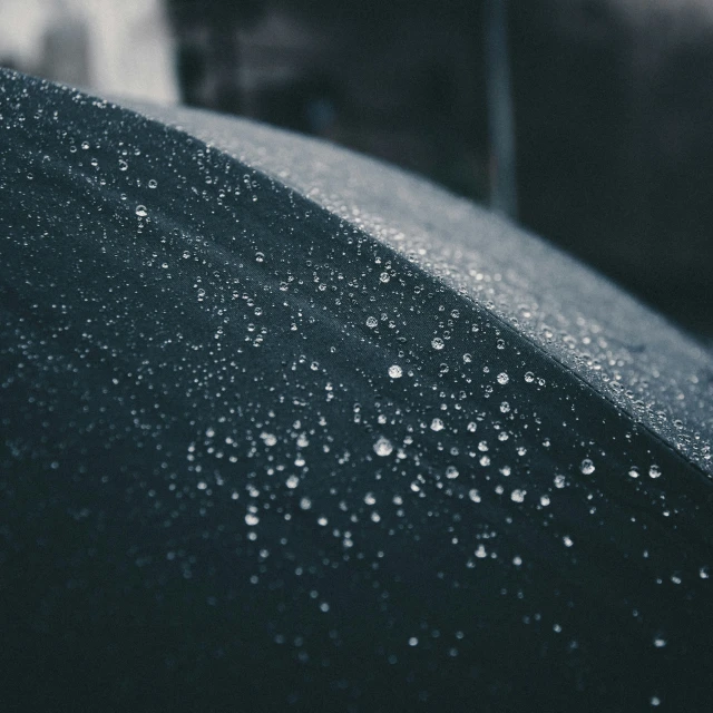 a black umbrella covered in rain next to a building