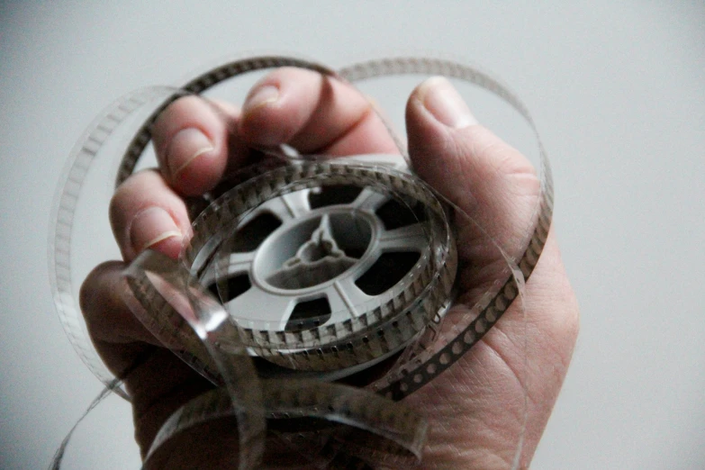 a person holding out an old film negative reel