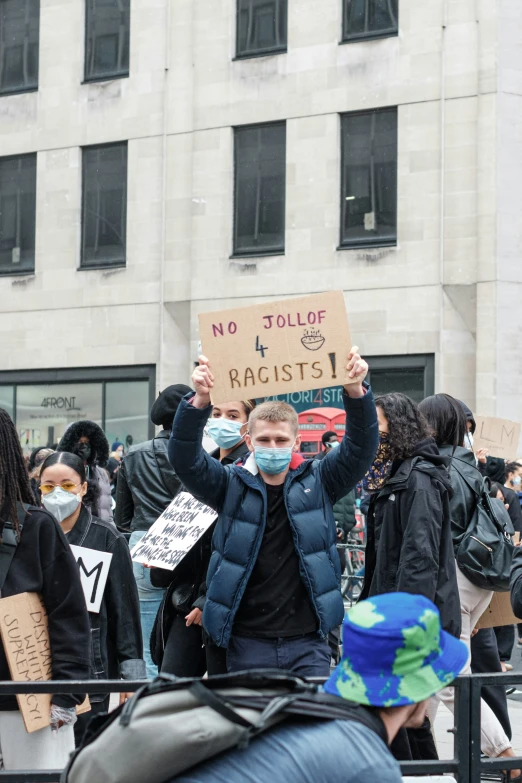 many people in the crowd have no faces and are holding signs