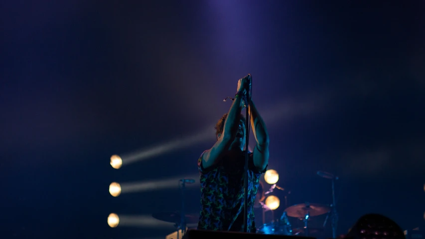 a woman holding her arms up on stage with spotlights