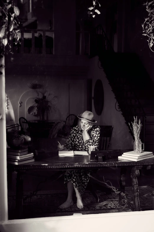 a lady is sitting at a table and working on her laptop