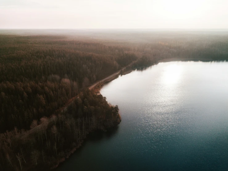 the lake is surrounded by forest on a foggy day