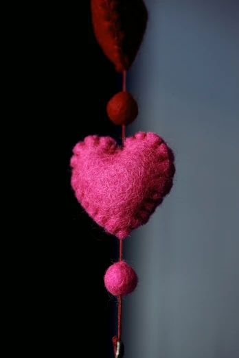 two pink hearts shaped like balls hanging from a hook