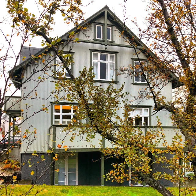 a home with white shutters on two levels sitting under trees