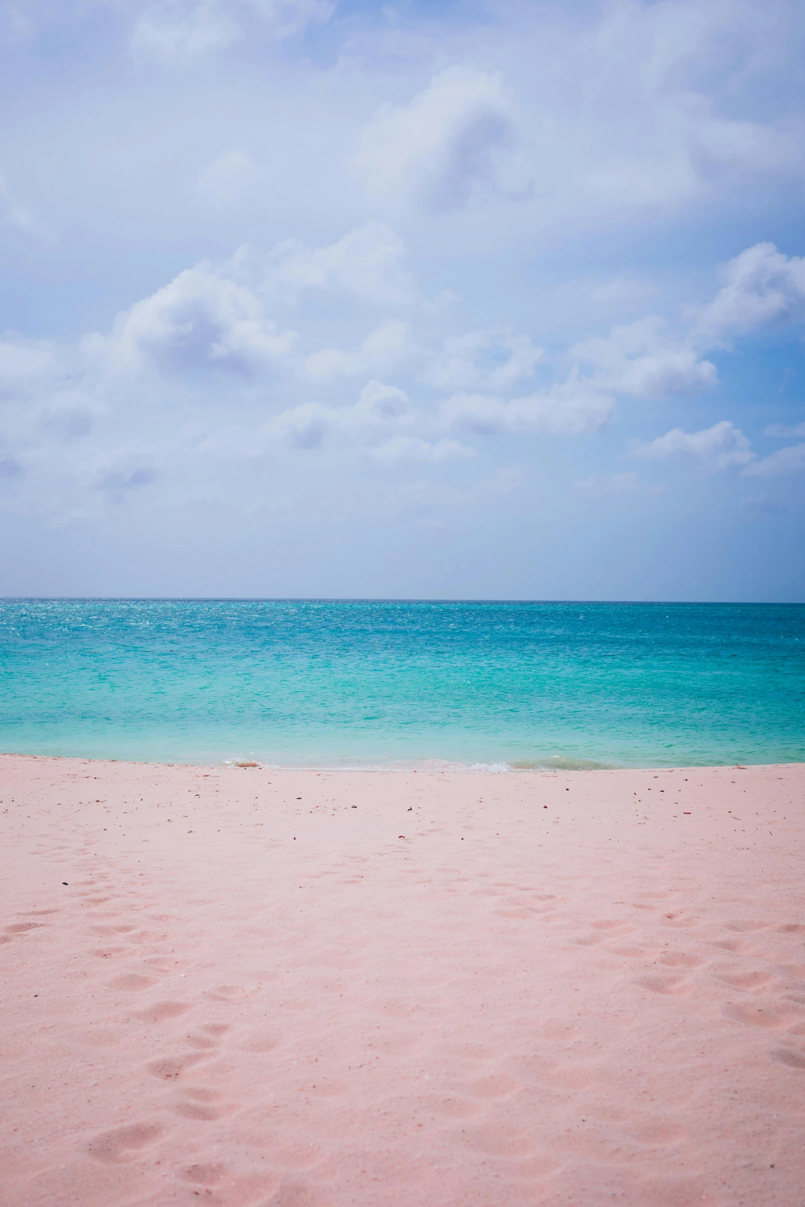 some sand and water blue sky and clouds