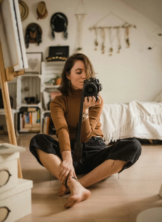 a woman kneeling on the floor with her camera in hand