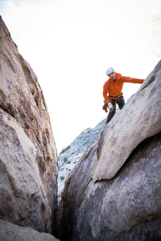 a man kneeling on a rock formation holding onto a small object