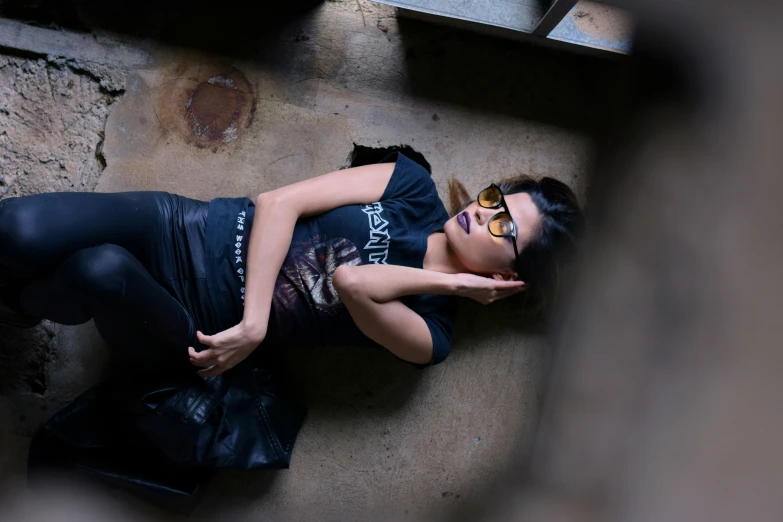 woman laying down on ground next to wall with leather bag