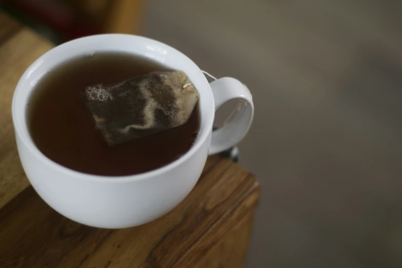 a mug with tea in it sitting on a wooden table