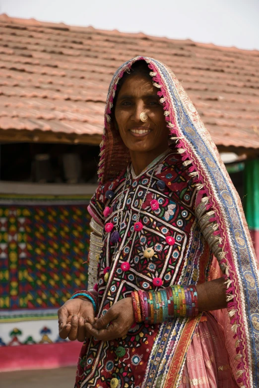 a smiling woman in colorful clothes stands outside