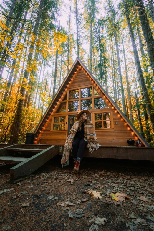 a woman in black shirt sitting outside of a cabin