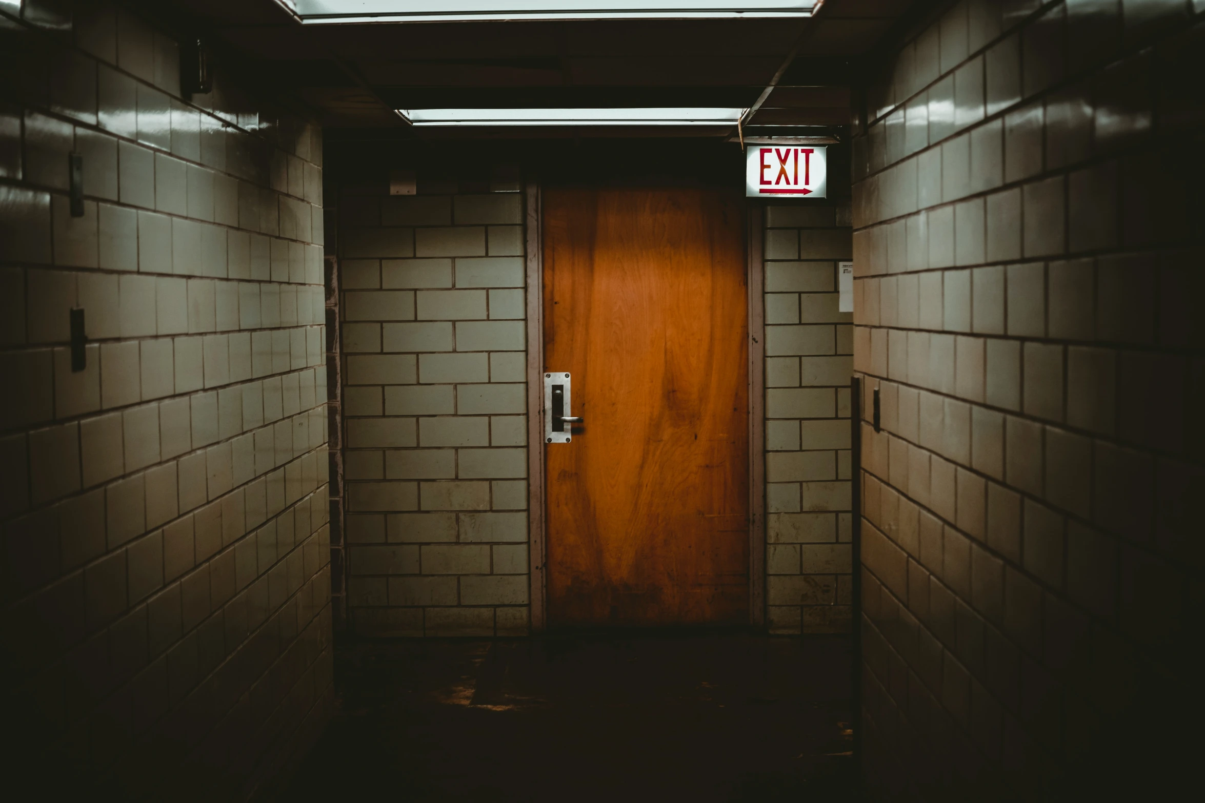 a wooden door at a dark, empty hallway