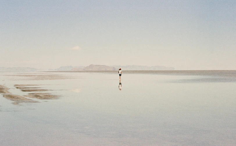 a person in the distance with an umbrella in their hands standing in shallow water