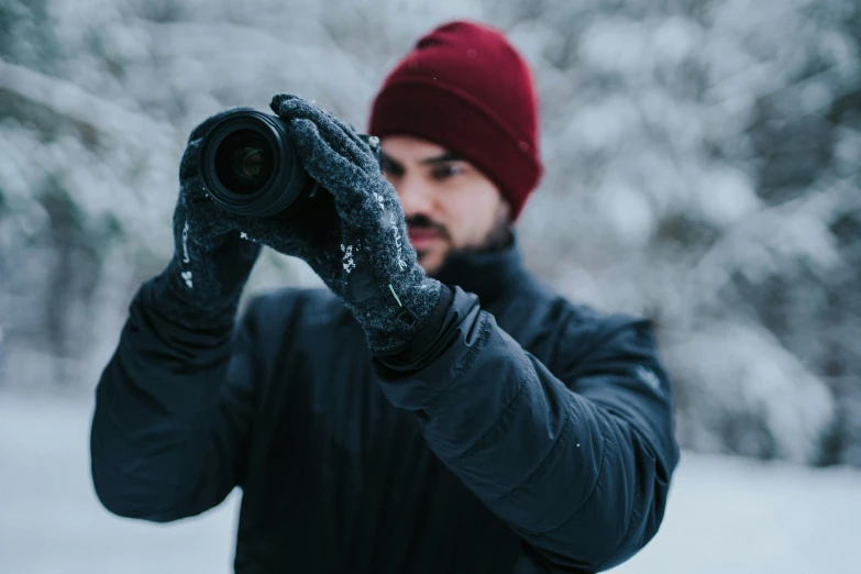 a person wearing black coat and beanie taking picture with camera