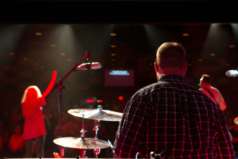 a drummer and his band at a concert with their microphones raised