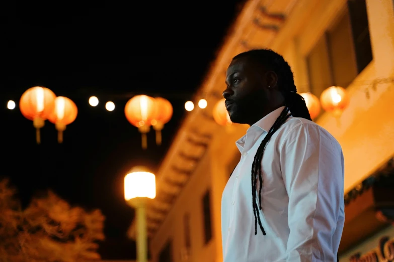 a man with a long id standing in front of lanterns