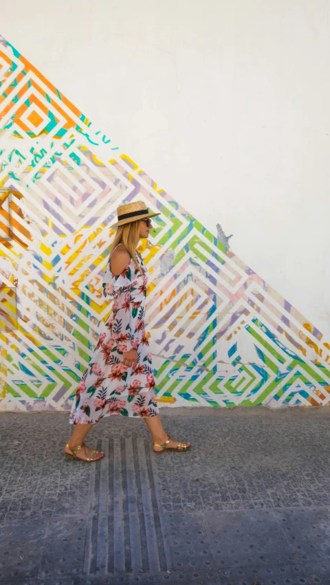 the woman is wearing a sunhat, walking down the street