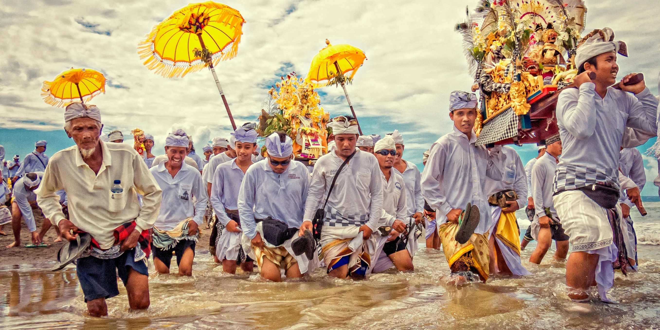 several men walk through the water carrying yellow umbrellas