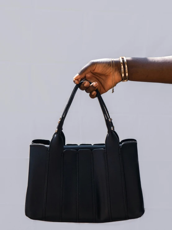 a hand holding a black leather bag with handle