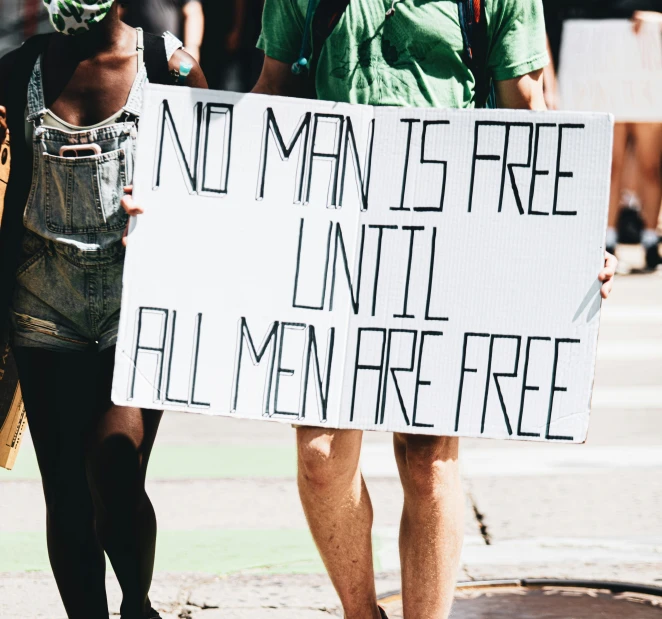 a woman holding a sign with a man walking behind her