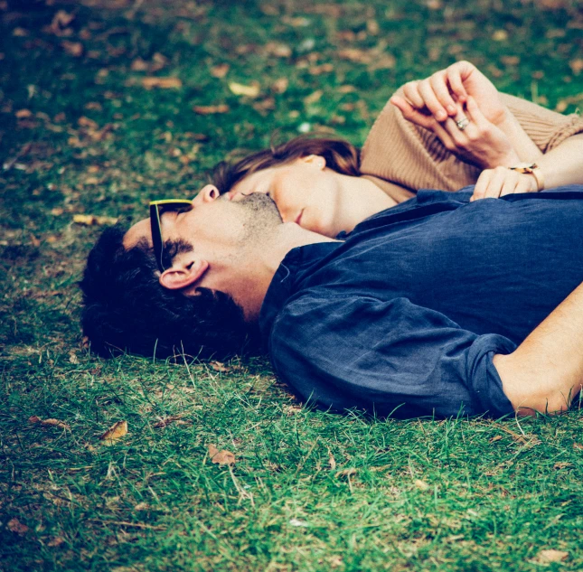 a man laying on the grass in front of some sunglasses