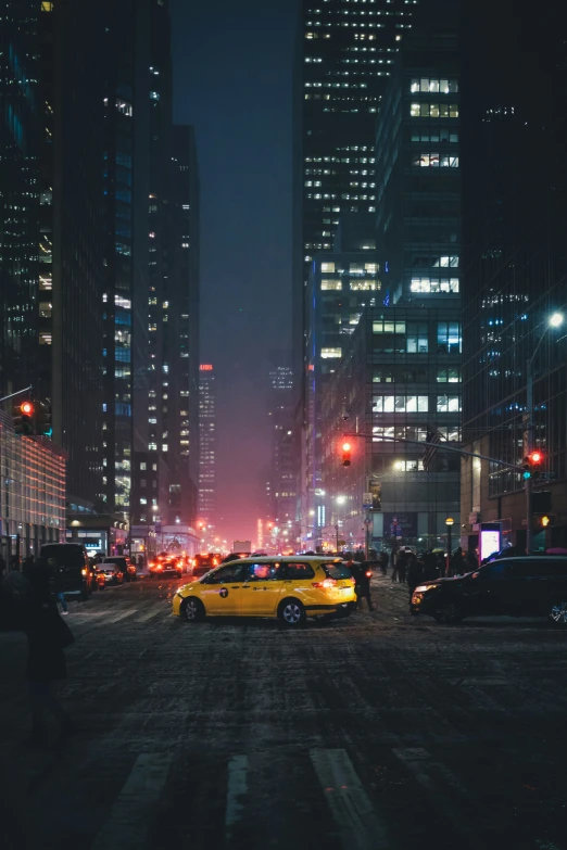 yellow cabs and other cars drive through the city streets at night