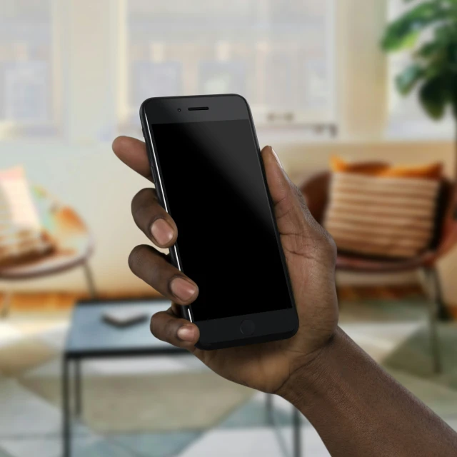 man holding up an lg smart phone next to living room