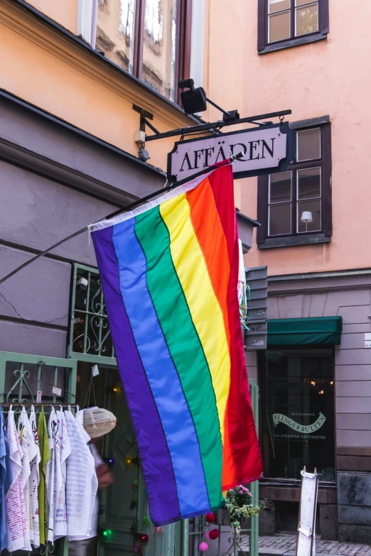 a large gay pride flag on display outside of a restaurant