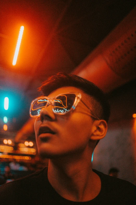 man with sunglasses and a cap standing under lights at night