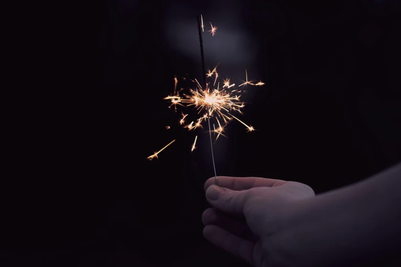 a hand holding a spark that is pointed into the sky