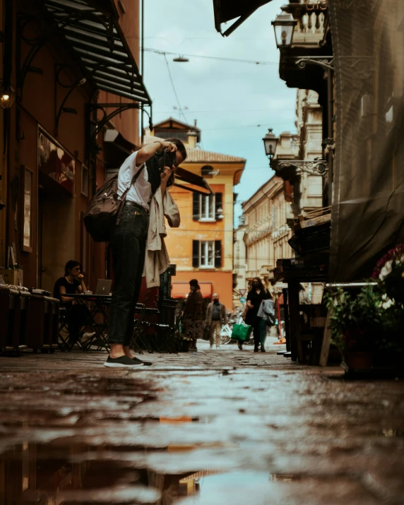 people and umbrellas standing in the rain outside an open store