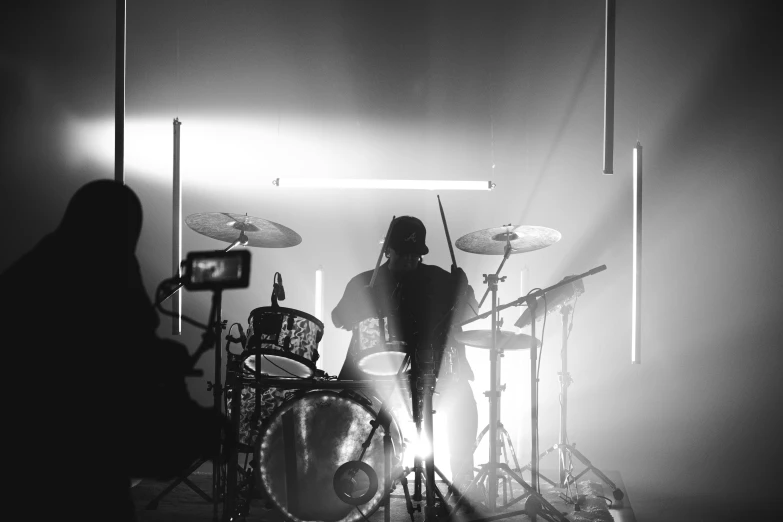 a person standing behind drums on stage