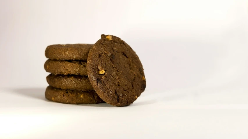 a stack of three chocolate cookies on a white table