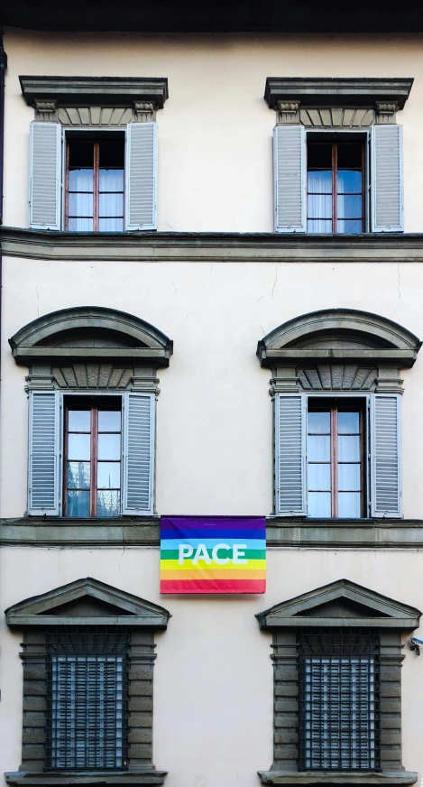 a large multi colored flag that is in front of a building