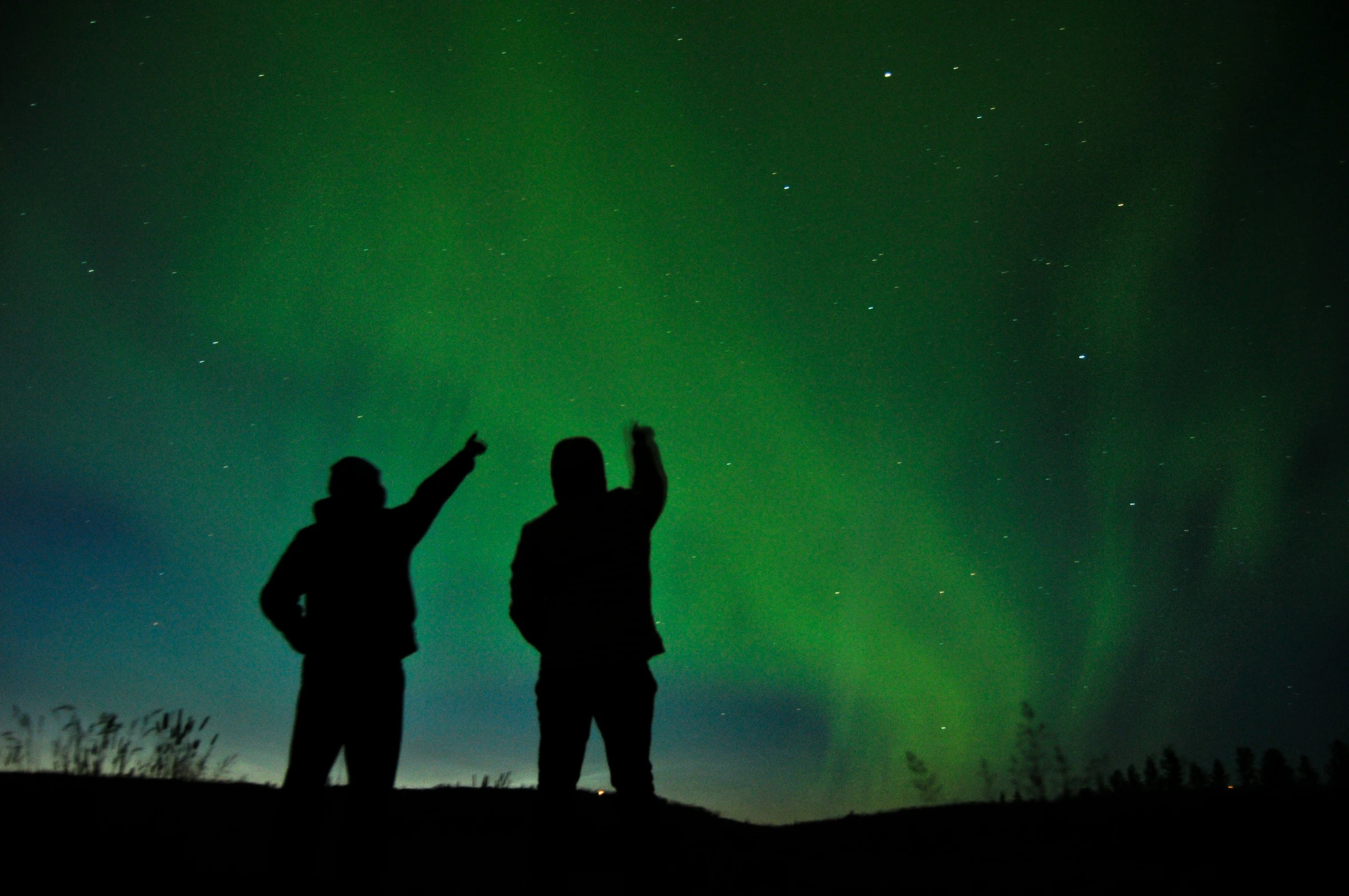 the people are looking up at the sky with a green light behind them