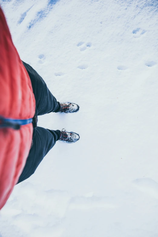 person in skis standing on snow next to a red jacket