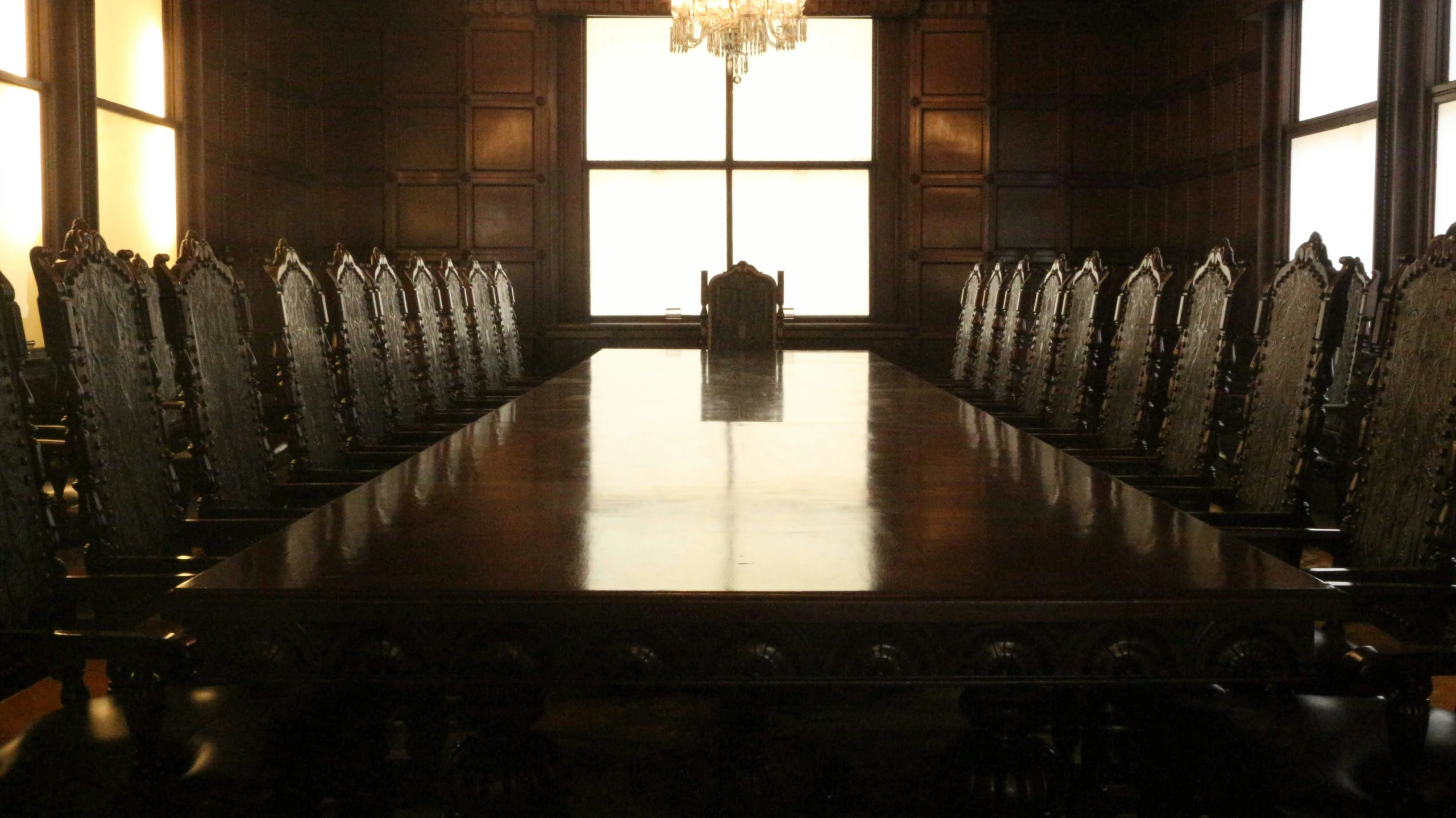 an ornate wooden table in front of two large windows