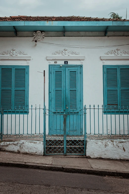 a white building with blue windows and metal gate