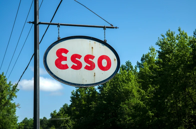 a white sign hanging from a power line next to some trees