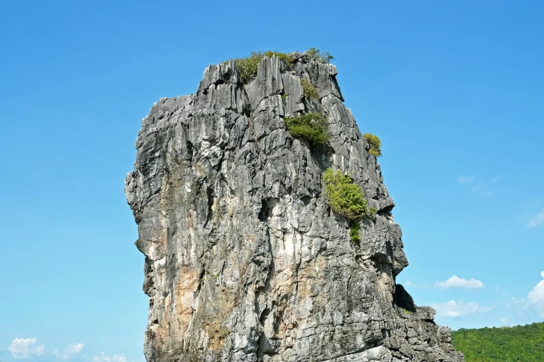 two boats are on the water in front of a big rock