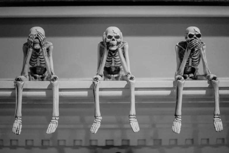 three skeleton sitting on chairs in a row