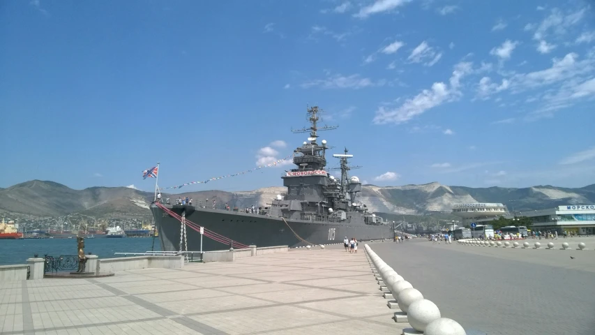 the battleship is parked next to a dock on the water