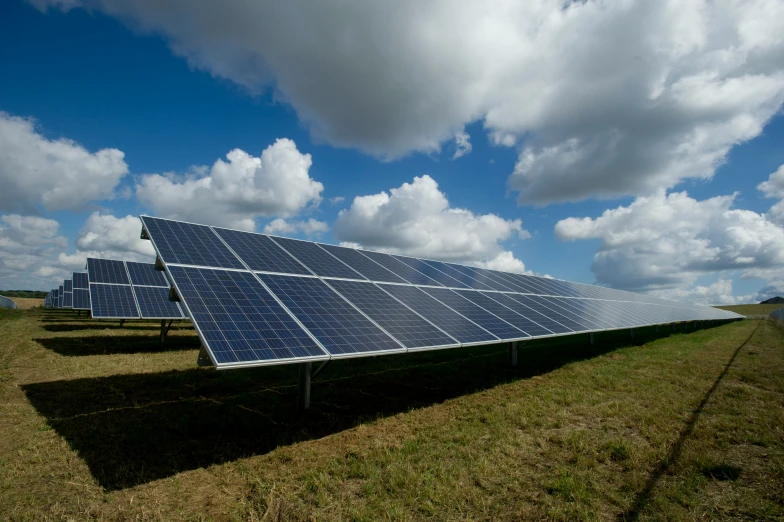 solar panels lined up on a field under blue skies