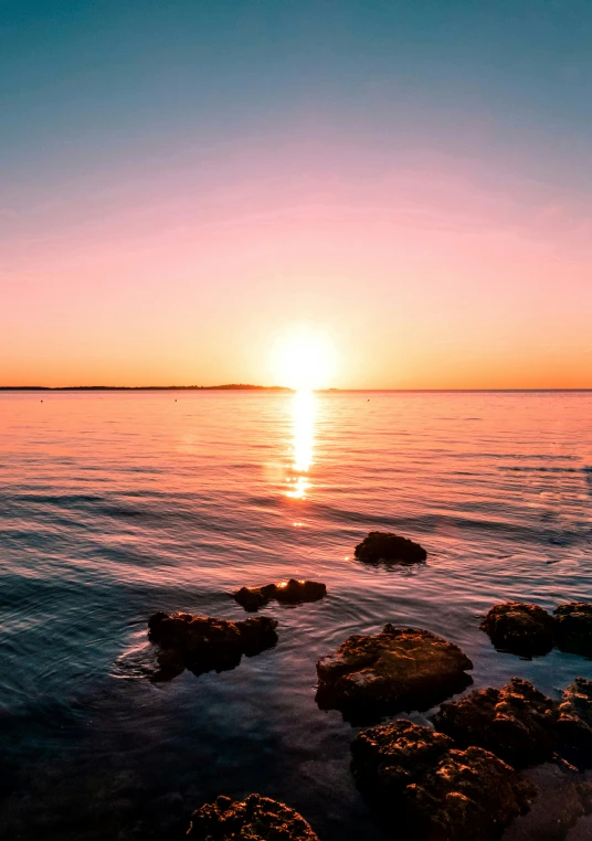 the sun is setting over the calm ocean