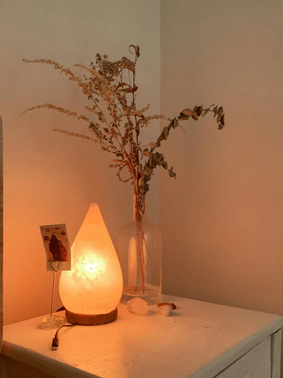 a decorative light is on a small table next to flowers and a mirror