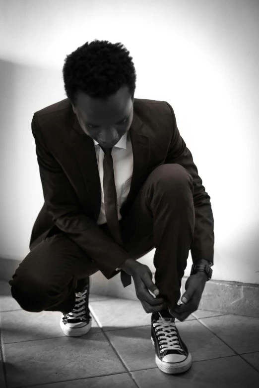 a young man in a suit tying his shoelaces